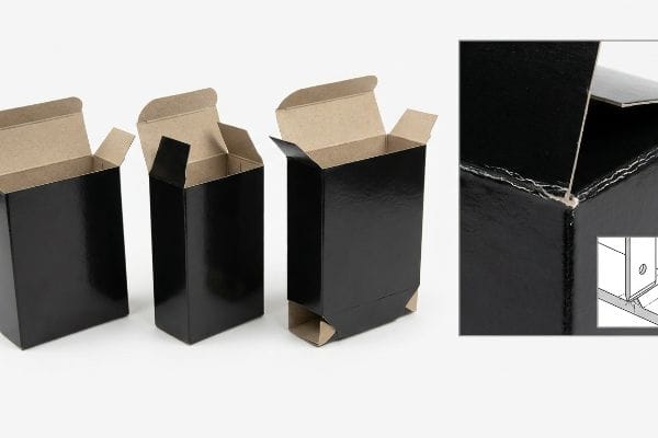 Black Tuck Box Crease Glossy black straight tuck boxes with kraft interiors, showing a corner crease and potential litho-cracking.