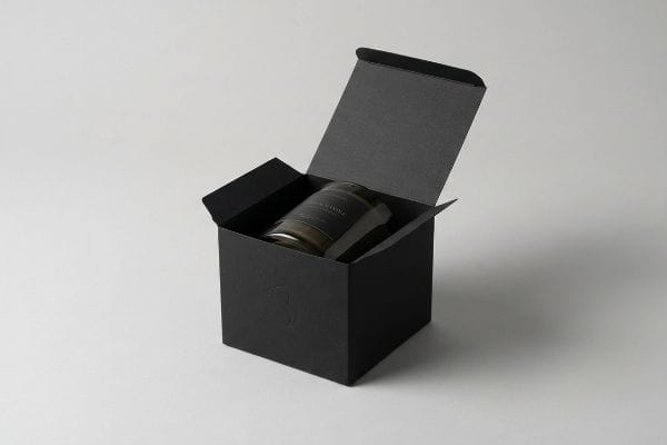 Black Candle Packaging Box An open black candle packaging box revealing a dark glass jar, showcasing premium brand equity with a subtle embossed logo.