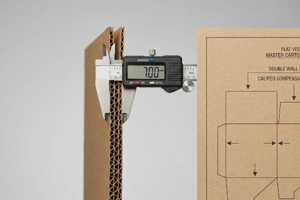 Caliper Measuring Double-Wall Thickness A digital caliper measures 7.00 mm thickness of double-wall corrugated cardboard, with a die-line drawing detailing Caliper Compensation.