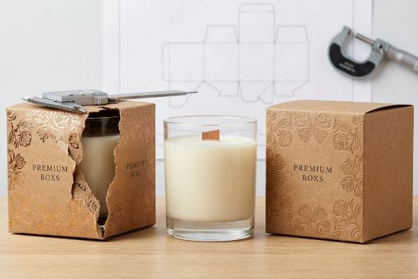 Candle Box Measurement Tools Embossed kraft Premium Boxes for candles, one open with a glass jar and caliper, next to a full candle and closed box, with a micrometer.