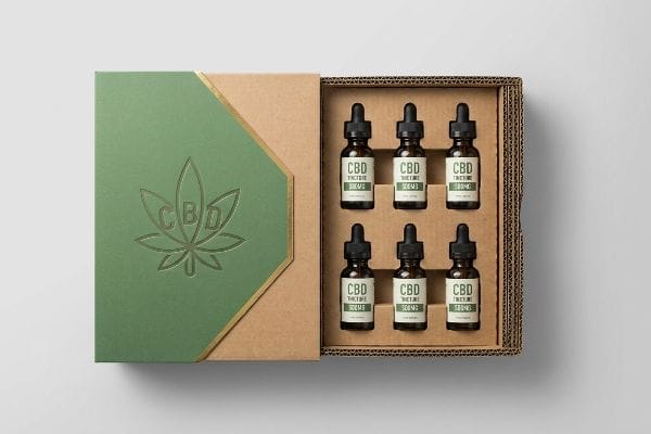 CBD-Tinktur-Displaybox In einer offenen, gewellten CBD-Displaybox befinden sich sechs bernsteinfarbene CBD-Tinkturfläschchen mit 500 mg Tropfverschluss und einem grünen Deckel mit einem Blattgoldmotiv.