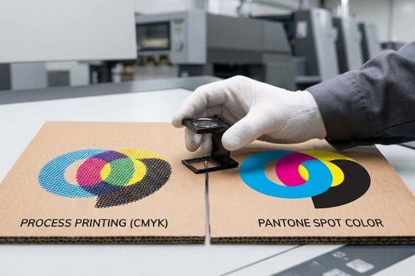 CMYK Pantone-Qualität Rohe Wellpappe zeigt CMYK-Prozessdruck-Halbtonpunkte im Vergleich zu vollflächigen Pantone-Sonderfarben, geprüft auf Druckqualität.
