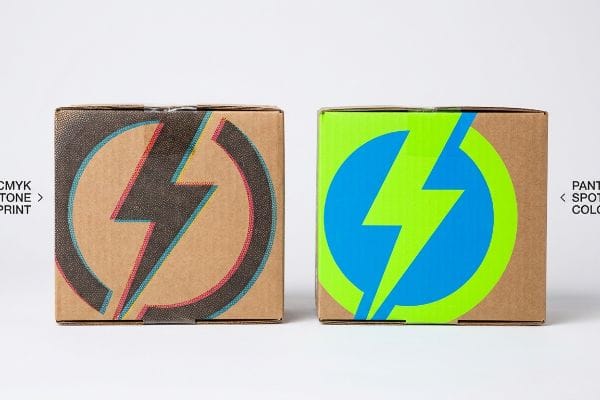 Two corrugated boxes display a lightning bolt logo, contrasting CMYK halftone print with a vibrant Pantone spot color flood.