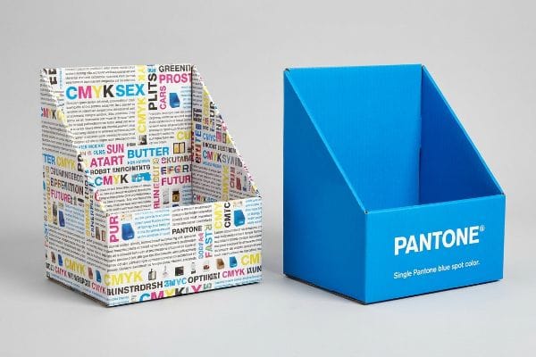 CMYK बनाम पैनटोन डिस्प्ले नालीदार डिस्प्ले बॉक्स जिन पर घने सीएमवाईके टेक्स्ट के साथ साफ पैंटोन नीले रंग का स्पॉट कलर है।.