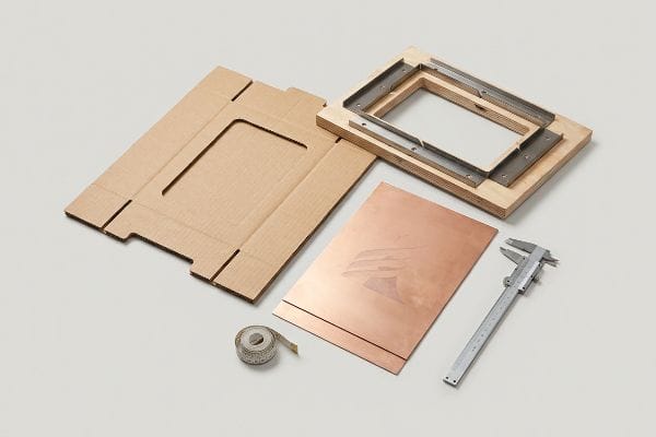 POP Display Production Tools Manufacturing tools for corrugated POP displays, featuring a steel rule die, copper printing plate with a logo, cardboard flat, measuring tape, and caliper.