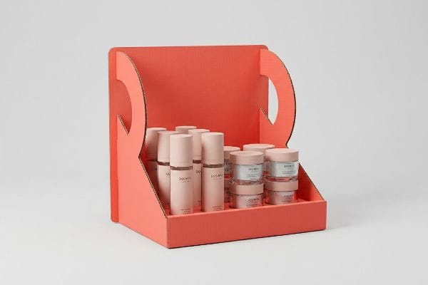 Coral corrugated cardboard display holds Doemte bottles and Ecosmet jars, showcasing cosmetic products.