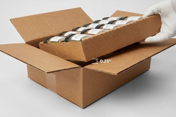 Offset Shipping Box Clearance Brown corrugated shipping box demonstrating a 0.25-inch geometric offset clearance for a tray of spice jars, preventing friction locking.