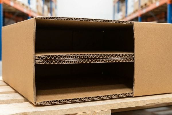 Corrugated Box Internal Structure Open double-wall corrugated box with internal shelves, showcasing visible flutes and kraft paperboard texture on a wooden pallet in a warehouse.