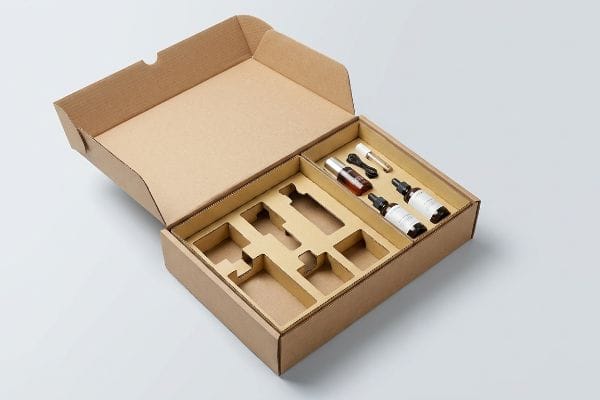 Corrugated Box Product Inserts An open corrugated display box features custom cardboard inserts with compartments holding various product bottles and droppers.