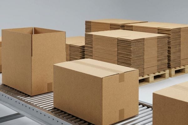 Warehouse scene with an open corrugated shipping box, a closed box on a roller conveyor, and flat-pack cardboard sheets on pallets.