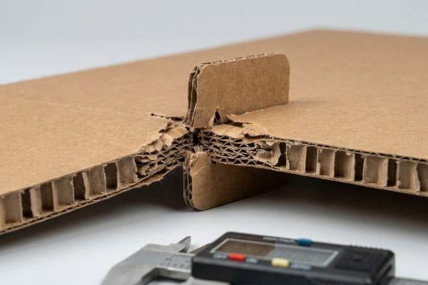 Caliper Corrugated Thickness Corrugated B-flute cardboard interlocking tab joint, with exposed fluting, measured for thickness by a digital caliper.