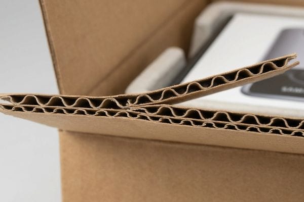Cardboard Flutes Detail Close-up of double-wall corrugated cardboard flutes, revealing the internal wave-like arches of protective packaging inside a brown box.