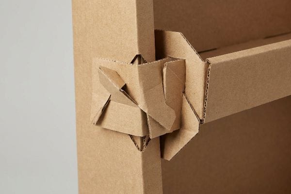Natural brown micro-fluted corrugated board forms an origami-style mono-material friction lock, showcasing interlocking tabs for plastic-free assembly.