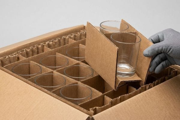 Glass Packaging Partitions Corrugated cardboard partitions securely cradle clear glass tumblers in a shipping box, showcasing engineered fragile packaging.