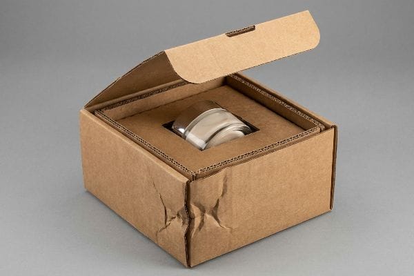 Corrugated Insert Protection Corrugated e-commerce packaging with an open lid, revealing a custom insert suspending a glass jar, featuring crumple zones for kinetic shock absorption.