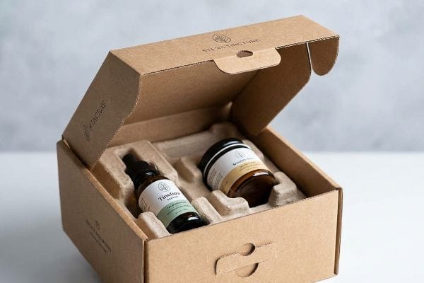 CBD-Geschenkverpackung Ein offener Wellpappkarton mit einem geformten Zellstoffeinsatz zum Schutz der Silas Tincture-Tropferflasche und der bernsteinfarbenen Glasflaschen von Wonder Balm.