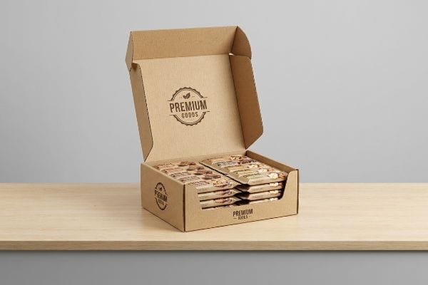 Premium Goods Display Box An open corrugated cardboard retail display box filled with Premium Goods snack packages on a light wooden surface.