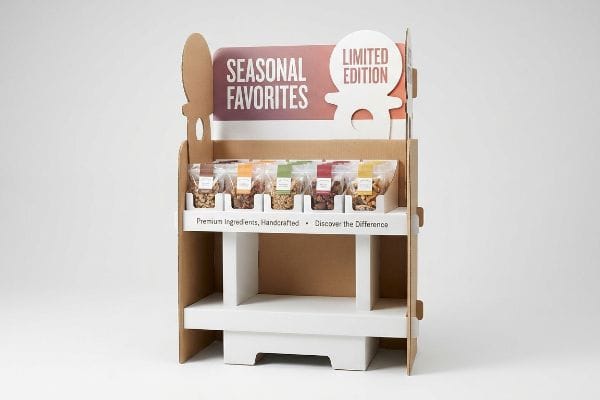 Cardboard Snack Display Corrugated cardboard retail display with "Seasonal Favorites" and "Limited Edition" signage, showcasing various snack bags on white shelves.