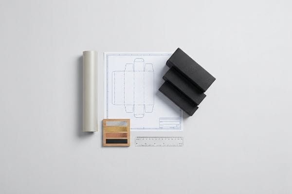 Packaging design process with a cosmetic box blueprint, black samples, metallic color swatches, and a ruler.
