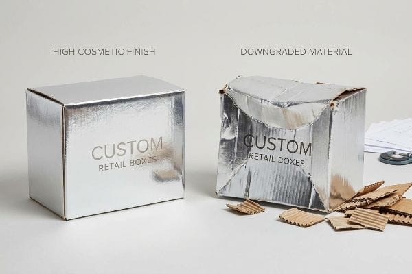 Cosmetic vs Downgraded Boxes Pristine silver custom retail box with High Cosmetic Finish next to a crushed box of Downgraded Material.