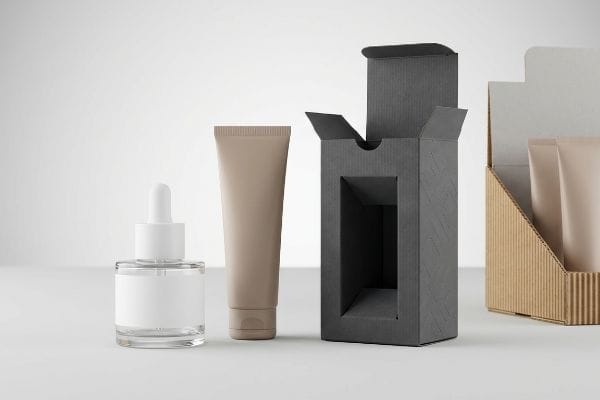 Cosmetic Packaging Display Cosmetic packaging display with glass dropper bottle, beige tube, dark grey folding carton, and corrugated retail stand.