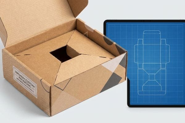 Custom Box Design Blueprint An open custom cardboard box with 'Premium Custom Packaging' label and internal insert, beside a tablet showing a structural blueprint.