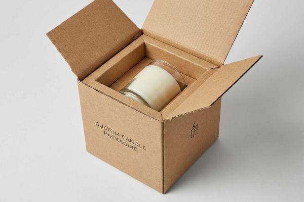 Caixa de papelão ondulado marrom com a inscrição "Embalagem Personalizada para Velas", contendo uma vela branca em um frasco de vidro com um encaixe personalizado para proteção durante o transporte.