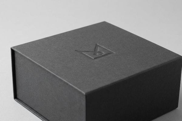 Dark grey textured gift box with a prominent debossed logo, showcasing premium tactile packaging.