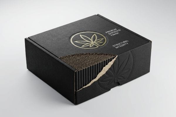 Black corrugated box with a cutaway revealing internal flutes, featuring a gold debossed cannabis leaf logo, 'Premium Debossed Finish', and 'Structural Integrity'.