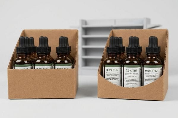article-image Brown corrugated paperboard featuring a precision-engineered swoop cutout ensures the THC-free compliance text on the bottom of a glass bottle remains visible.