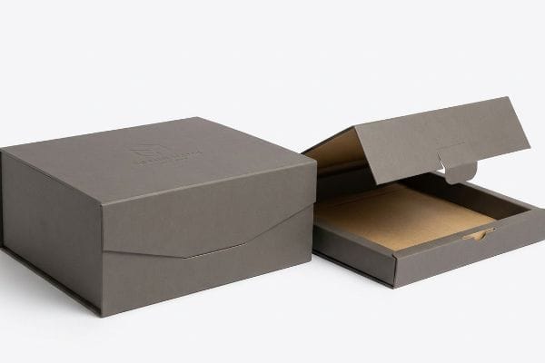 Dark grey Charles Martell London gift boxes, one closed, one open revealing a kraft interior and structural die-cut tab closure.