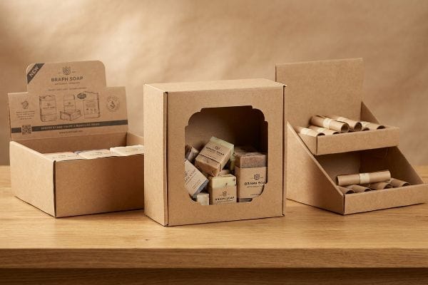 Three natural kraft display boxes featuring Brafh Soap bars and rolled paper samples, one with a decorative die-cut window and 'New' header.
