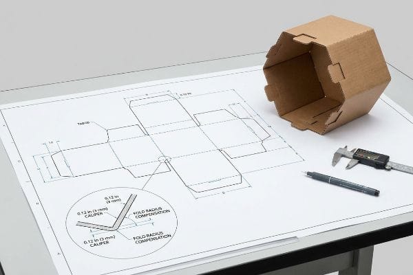 Hexagon Box Dieline Design Brown corrugated hexagon box next to a dieline blueprint detailing 0.12 in (3 mm) Caliper and Fold Radius Compensation.