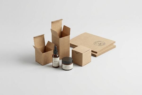 段ボール製の化粧品パッケージ。「生命のしずく」と書かれたガラス製のスポイトボトル、瓶、そして開いた箱が特徴で、持続可能な素材が使用されていることが強調されている。.