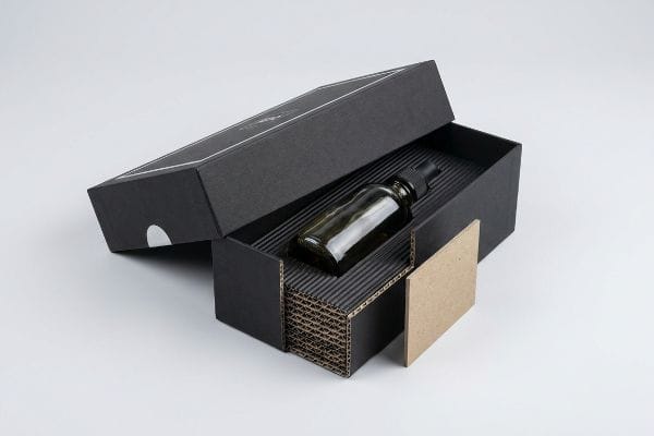 E-flute Gift Box Packaging Black micro-fluted corrugated gift box open, revealing a glass dropper bottle and E-flute insert for botanical products.