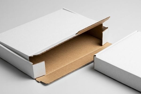 E-Welle-Wellpappkarton Ein weißer, E-Wellen-Wellpappkarton ist geöffnet und gibt den Blick auf sein dünnes 1,5 mm Mikrowellprofil und sein braunes Inneres frei; daneben steht ein geschlossener Karton.