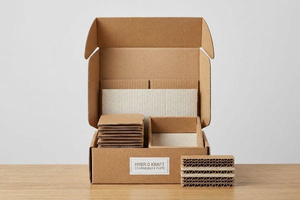 Hybrid Kraft E-Flute Box Hybrid Kraft Eco-Friendly E Flute shipping box, open and filled with corrugated cardboard inserts, alongside a stack of visible E-flute board.