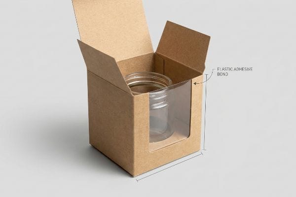 Open Kraft paperboard box with clear polymer window, showcasing an empty glass jar and an Elastic Adhesive Bond.