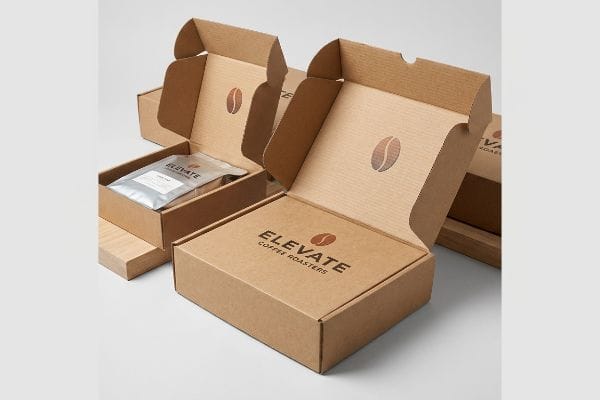 Elevate Coffee Boxes Two open kraft coffee boxes, one containing a silver coffee bag, both featuring the Elevate Coffee Roasters logo and a coffee bean icon.
