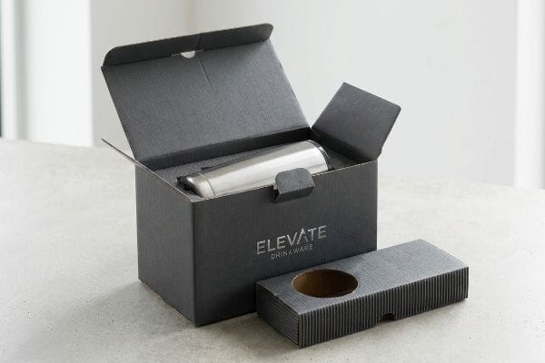 Elevate Tumbler Box Packaging An open dark gray Elevate Drinkware custom tumbler box reveals a stainless steel tumbler nestled in a protective foam insert.