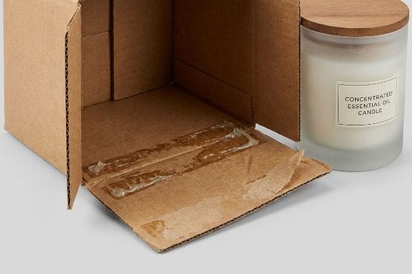 Dissolved Adhesive Candle Box Open cardboard box showing dissolved PVA adhesive on bottom flaps, beside a frosted Concentrated Essential Oil Candle.