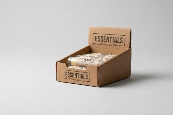 Essentials Lip Balm Display Brown corrugated cardboard display box holding multiple Essentials Natural Lip Balm tubes, designed for point-of-purchase.