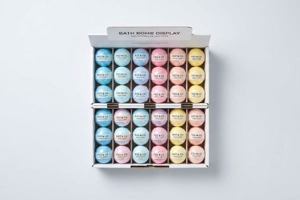 Fizz & Co. Display An open white cardboard display box showcases 48 Fizz & Co. bath bombs in blue, pink, purple, and yellow, labeled "Bath Bomb Display Premium Collection".