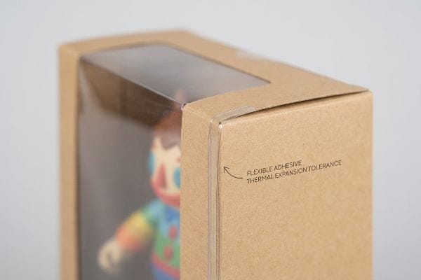 Brown kraft paper box with clear PET window, highlighting "Flexible Adhesive Thermal Expansion Tolerance" for packaging.