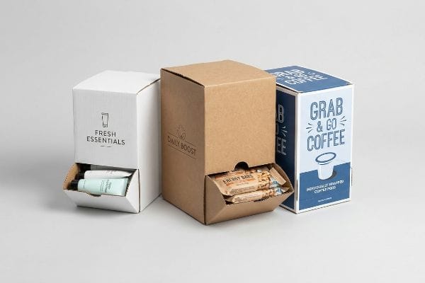 Custom Dispenser Boxes Three custom dispenser boxes: white Fresh Essentials, kraft Daily Boost Energy Bars, and blue Grab & Go Coffee pods.