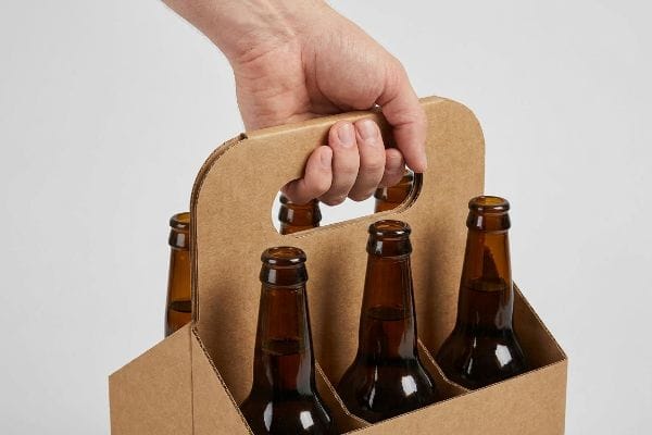 茶色の段ボール製の6本入りビールケースに琥珀色のビール瓶が詰められており、持ち手には人間工学に基づいた強化されたハンドルが備え付けられており、快適に持ち運べるようになっている。.