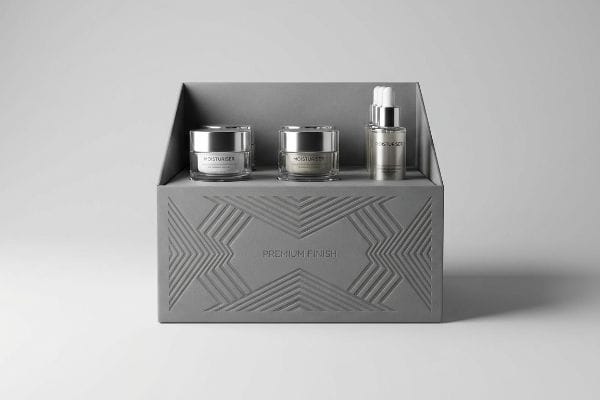 Grey cosmetic packaging box with "Premium Finish" inward debossing, holding three silver-capped Moisturiser products.