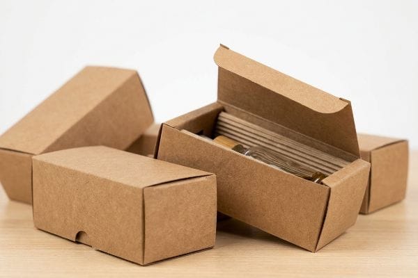 Individuell gestaltete CBD-Boxen aus Kraftpapier Individuell gestaltete CBD-Verpackungsboxen aus braunem, ungebrauchtem Kraftkarton, eine davon geöffnet, gibt den Blick frei auf Glasampullen mit Tinkturen und mikrogeriffelte Wellpappeinsätze.