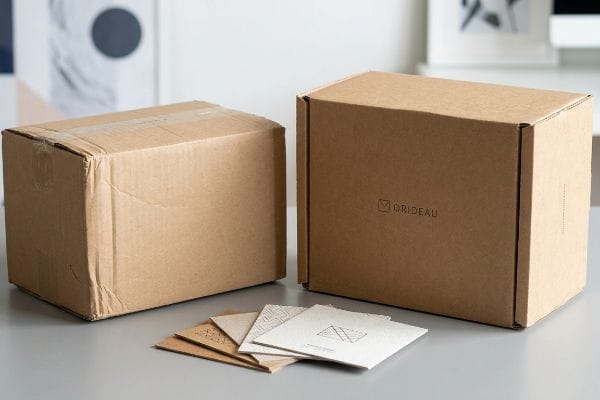 Branded Packaging Boxes Brown kraft cardboard boxes, one branded Orideau, and small paper cards for product packaging and brand communication.