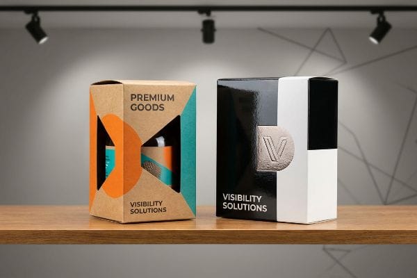 Visible Product Packaging Two 'Visibility Solutions' packages: kraft 'Premium Goods' box and glossy black-white box with embossed 'V' logo.